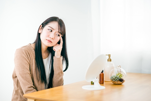 鏡の前で目もとを気にする女性
